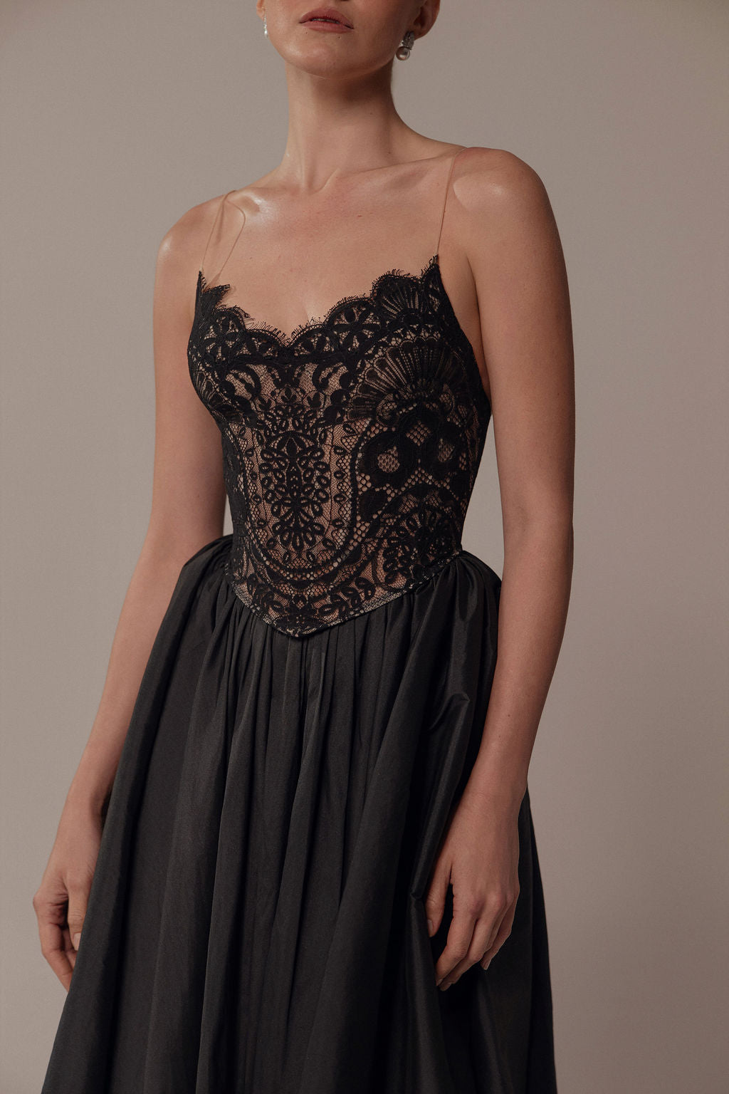 אישה לבושה בשמלת Luna מקולקציית Evening 2026 של Dror Kontento, עם מחוך תחרה שקוף וחצאית מתנפנפת, עומדת על רקע ניטרלי, ראשה מוטה ופניה חלקית מחוץ לפריים.