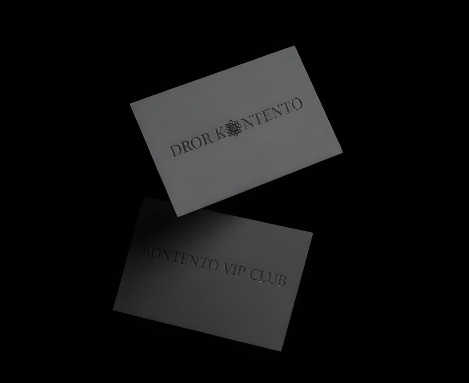 שני כרטיסי ביקור על רקע שחור; בכרטיס העליון כתוב DROR KONTENTO עם עיצוב פרחוני דקורטיבי, ובכרטיס התחתון כתוב KONTENTO VIP CLUB.