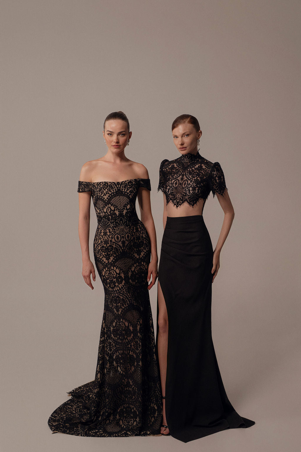 שתי נשים מצטלמות בשמלות תחרה שחורות ואלגנטיות – האחת לובשת את שמלת Hila מקולקציית ערב 2026, שמלת כתפיים חשופות; השנייה לובשת חולצת בטן וחצאית עם חתך גבוה. שתיהן עם שיער חלק, מקרינות אלגנטיות ערבית מודרנית.